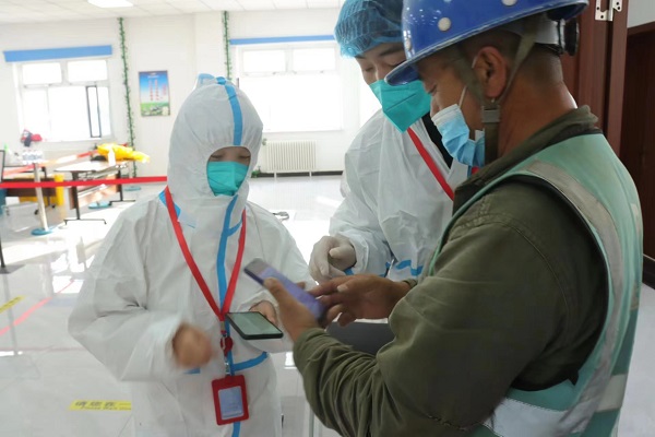 盧凱同志參加核酸檢測志願服務工作（圖右，穿着白色醫用防護服的青年）.jpg